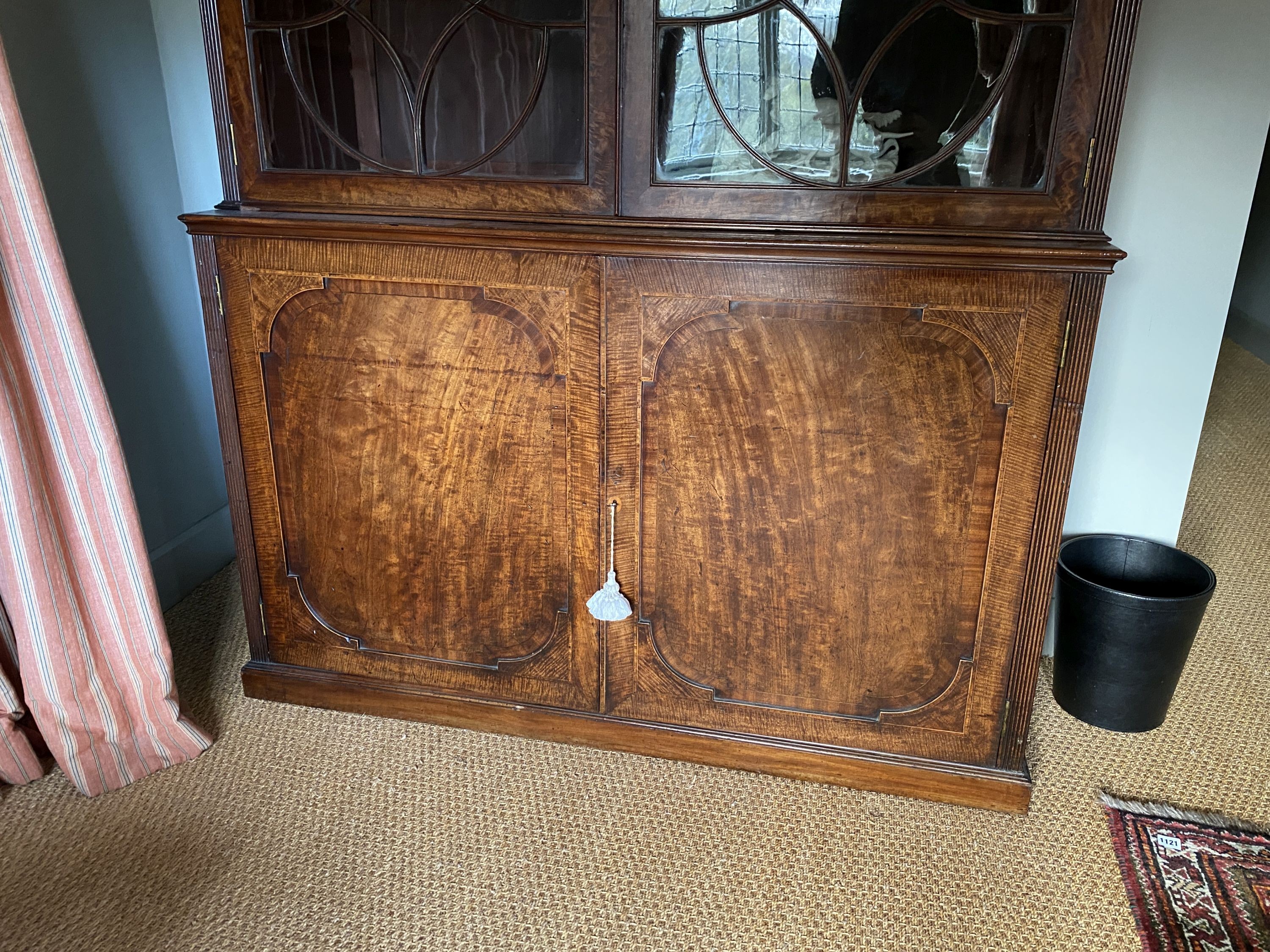 A George III mahogany bookcase, with two astragal glazed doors enclosing adjustable shelves over two panelled doors, width 142cm depth 47cm height 236cm